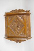 A Continental carved oak corner cupboard of small proportions with radial and floral carved designs,