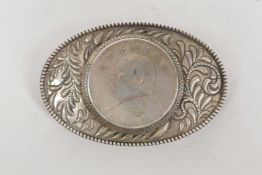 A Chinese white metal oval belt buckle set with a facsimile coin, character stamp verso, 3½" x 2"