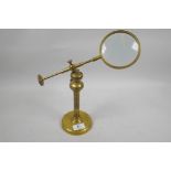 A brass industrial style desk top magnifying glass on an adjustable stand, glass 4" diameter
