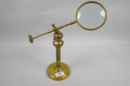 A brass industrial style desk top magnifying glass on an adjustable stand, glass 4" diameter