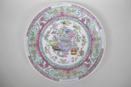 A Chinese famille rose enamelled porcelain charger decorated with vases of flowers, gourds and the