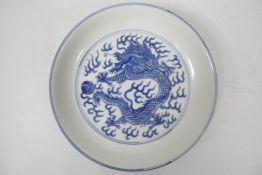 A Chinese blue and white porcelain cabinet dish decorated with a dragon chasing the flaming pearl,