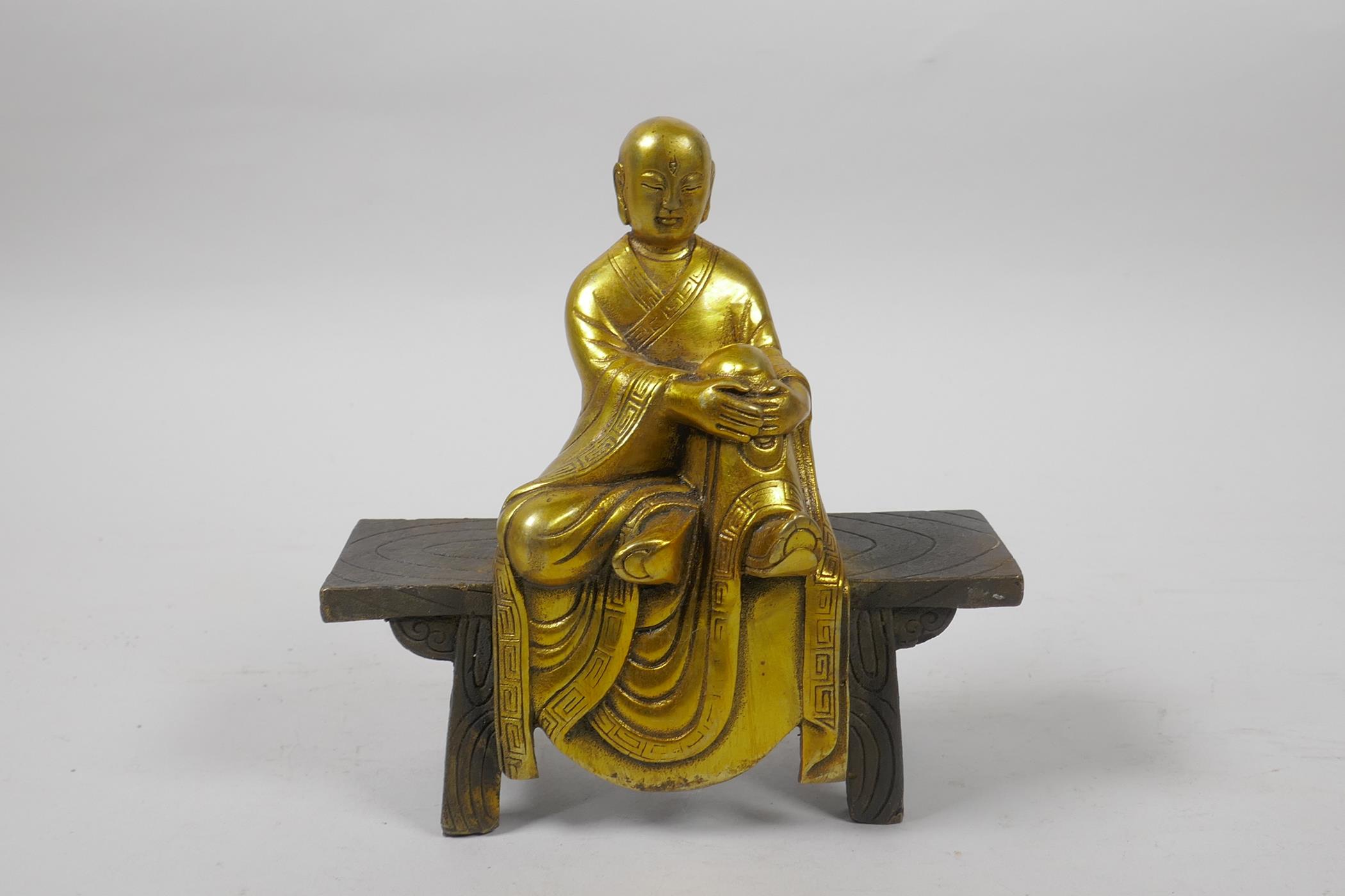 A Chinese gilt bronze figure of Buddha seated on a bench, 5½" high