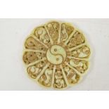 A Chinese carved jade roundel carved with a Yin and Yang centre surrounded by the animals of the