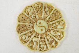 A Chinese carved jade roundel carved with a Yin and Yang centre surrounded by the animals of the