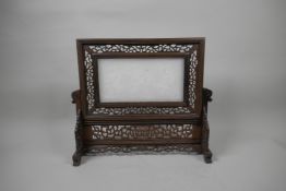 A Chinese white jade table screen in a pierced hardwood stand, with carved decoration of three
