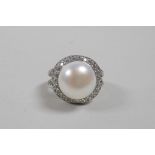 A silver dress ring set with a large freshwater pearl encircled by cubic zirconium, approximate size