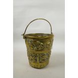 A C18th/19th brass bucket with repousse decoration of angelic figures, griffons and figures on