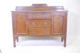 A 1930s oak breakfront sideboard with two cupboards flanking three drawers, 55" x 19" x 39"