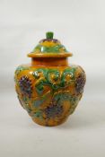 A large Chinese Sancai glazed pottery jar and cover with raised scrolling lotus flower decoration,