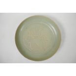 A Chinese Song style celadon glazed dish with incised figural decoration, character inscription to