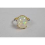 A silver gilt ring set with a large opal and diamond shoulders, approximate size 'P'