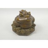 A Chinese filled bronze figure of a three footed toad (Chan-Chu) sitting on a pile of coins,