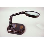 A small table top brass magnifying glass on a polished wooden base, glass 3" diameter