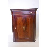 A Georgian mahogany hanging corner cupboard with inlaid decoration depicting Old Father Time, 37"