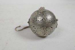 A pierced white metal ball incensor with Islamic decoration, opening to reveal a gimbal mounted