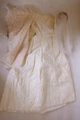 An embroidered cream satin wedding dress, and two veils