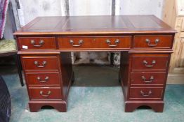 A Victorian style mahogany five drawer pedestal desk with six drawers and a cupboard, with leather
