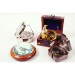 A hardwood cased paperweight compass, 4" diameter, together with three brass cased sighting