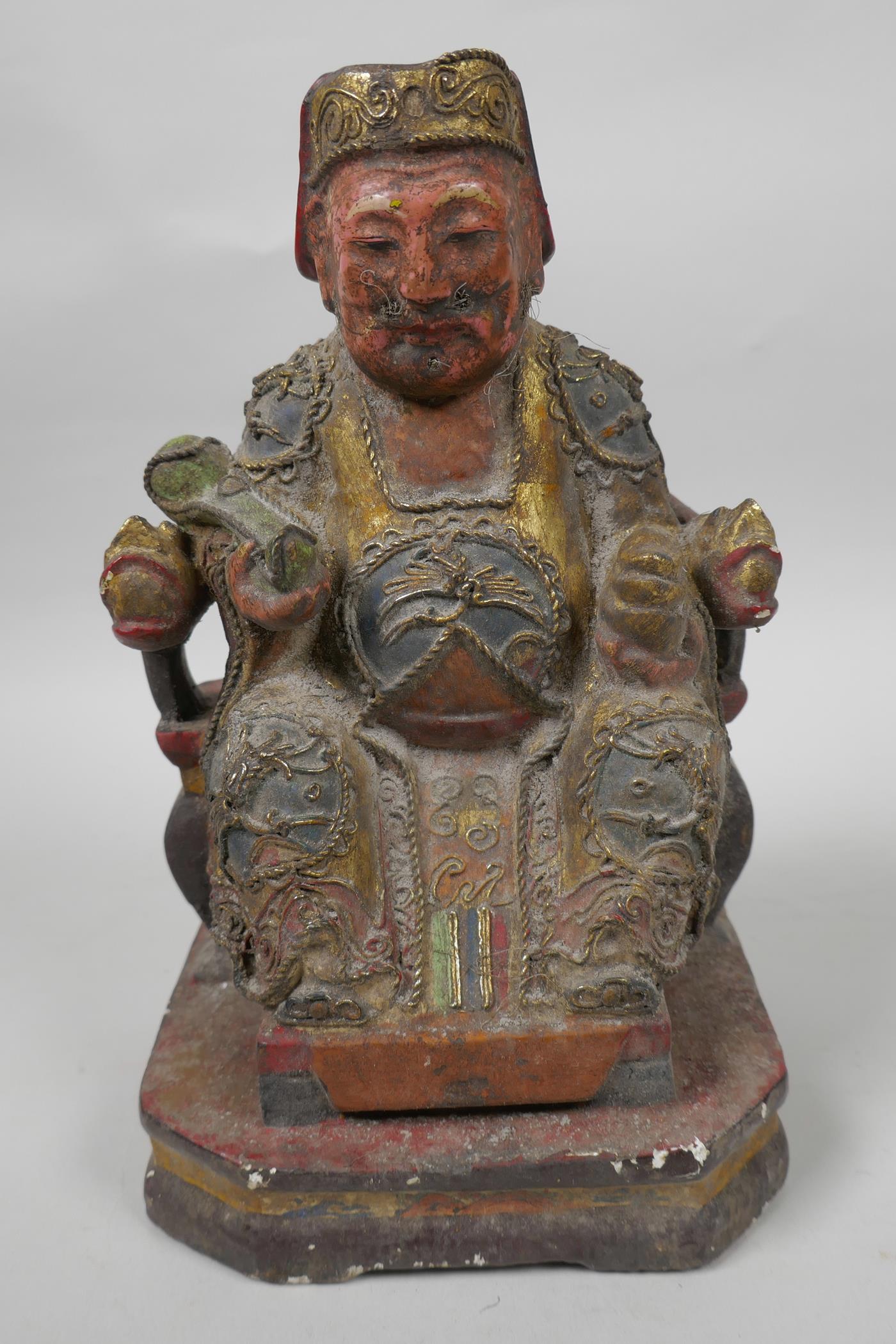 A Chinese painted wooden figure of a dignitary wearing fine robes with wired decoration, seated on a