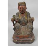 A Chinese painted wooden figure of a dignitary wearing fine robes with wired decoration, seated on a