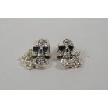 A pair of silver skull earrings