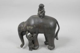 A Chinese white metal figure of an elephant with two children, the elephant having paw feet, 7" high
