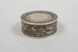A Chinese white metal coin box with carp and lotus flower decoration to side, 2" diameter