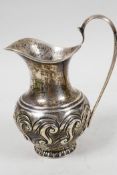 An Art Nouveau silver cream jug with embossed scrolling decoration, hallmarked Birmingham 1902 (87