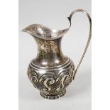 An Art Nouveau silver cream jug with embossed scrolling decoration, hallmarked Birmingham 1902 (87