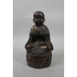 A Chinese bronzed and gilt metal figure of a childlike Buddha, 8½" high
