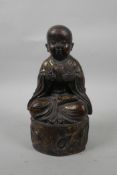 A Chinese bronzed and gilt metal figure of a childlike Buddha, 8½" high