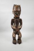 An African carved wood and plastered tribal figure with shell set eyes, 20" high, possibly from