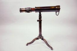 A small table top brass telescope, 9" long, on tripod stand