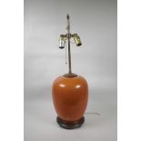 An Oriental coral glazed porcelain lamp with brass fittings on a hardwood base, 26" high