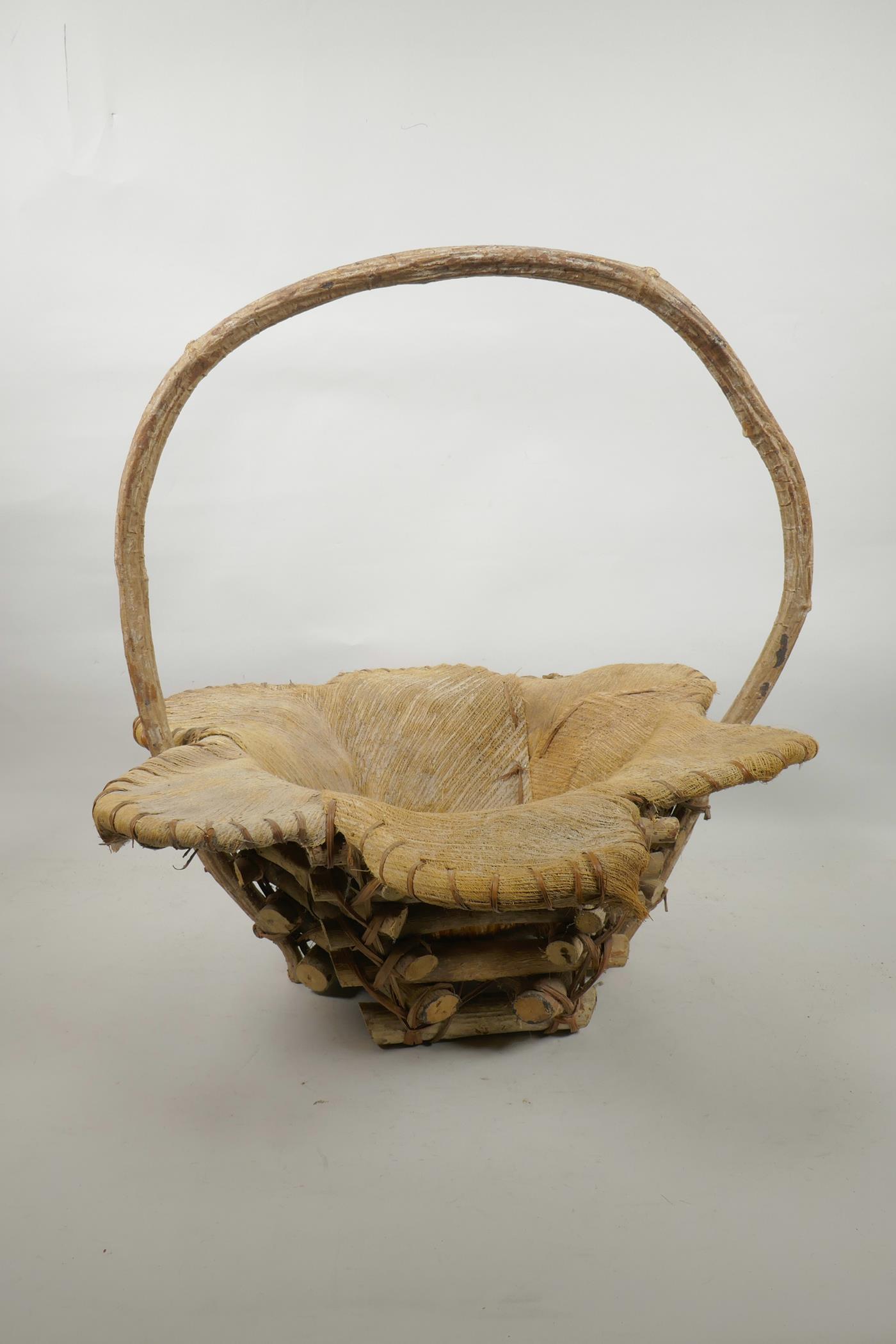 A wood and coconut husk petal shaped basket, 18" high