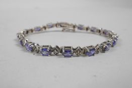 A silver and tanzanite line bracelet, 7" long