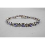 A silver and tanzanite line bracelet, 7" long