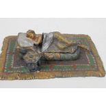 A cold painted bronze figure of a girl lying on a bed, 6¼" long