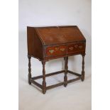An C18th oak fall front bureau, with shaped and stepped interior and two drawers, raised on turned