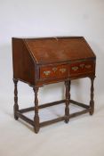 An C18th oak fall front bureau, with shaped and stepped interior and two drawers, raised on turned