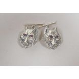 A pair of silver cufflinks in the form of wolf heads