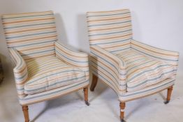 A pair of contemporary armchairs with swept arms, raised on turned oak supports