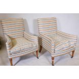 A pair of contemporary armchairs with swept arms, raised on turned oak supports