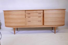A 1970s teak breakfront side board with four drawers flanked by two doors, 73½" x 19", 30½" high
