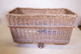 A large wicker laundry basket on three wheels, 21" x 43", 28" high