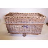 A large wicker laundry basket on three wheels, 21" x 43", 28" high