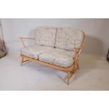 An Ercol Windsor 203 two seater sofa in blonde beechwood, dating from the early 1970s, featuring a