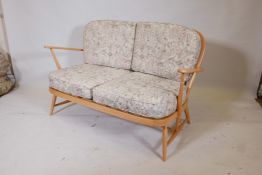 An Ercol Windsor 203 two seater sofa in blonde beechwood, dating from the early 1970s, featuring a