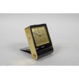 A Jaeger travelling alarm clock in a gilt and black metal case, with square gilt dial and Arabic